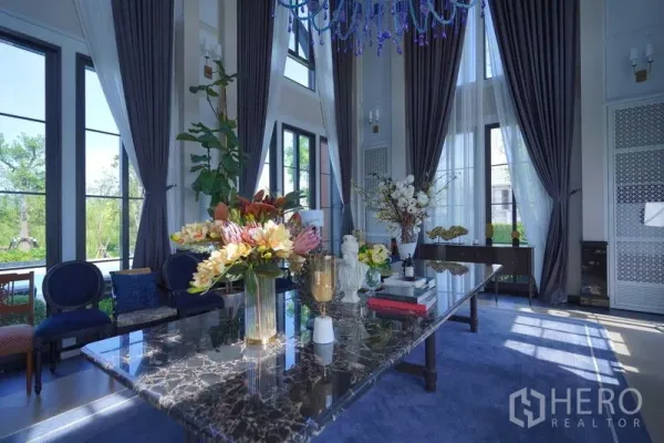 Detached House for sale in Bang Kapi, Bangkok - Elegant living room with marble table, tall windows, and heavy drapes.