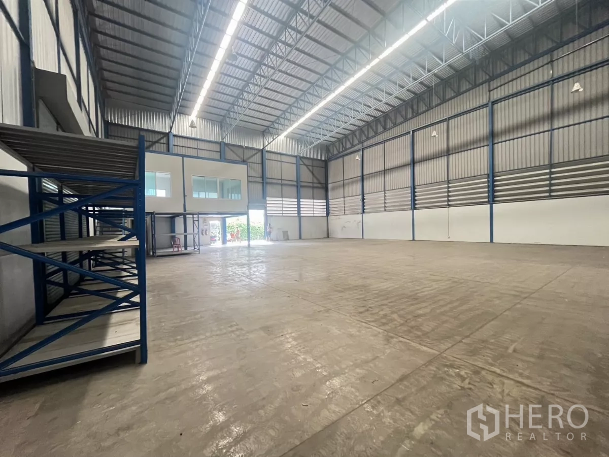 Factory for rent in Phra Pradaeng, Samut Prakan - Open factory floor with tall ceiling, in-house office with glass windows, metal shelving and bright strip lighting.