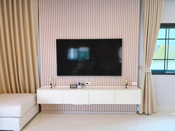 Detached House for rent in Bang Phli, Samut Prakan - Feature wall with mounted flat-screen TV, floating console and full-length curtains.