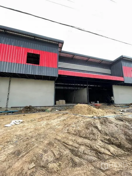 Warehouse for rent in Pathum Thani - Angled facade showing multiple loading bays and a wide setback for truck access.
