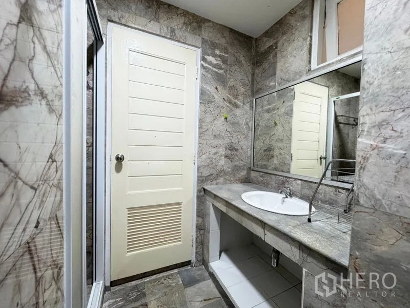 Townhouse for rent or sale in Suan Luang, Bangkok - Marble-clad bathroom with wide countertop, mirror and shower entrance