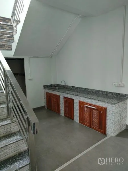 Factory for rent in Ban Phaeo, Samut Sakhon - Under-stair pantry with granite countertop, sink, and wooden cabinets.