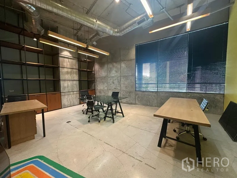 Office Space for rent - Workspace with large windows, exposed ducts, wall shelving and multiple desks.