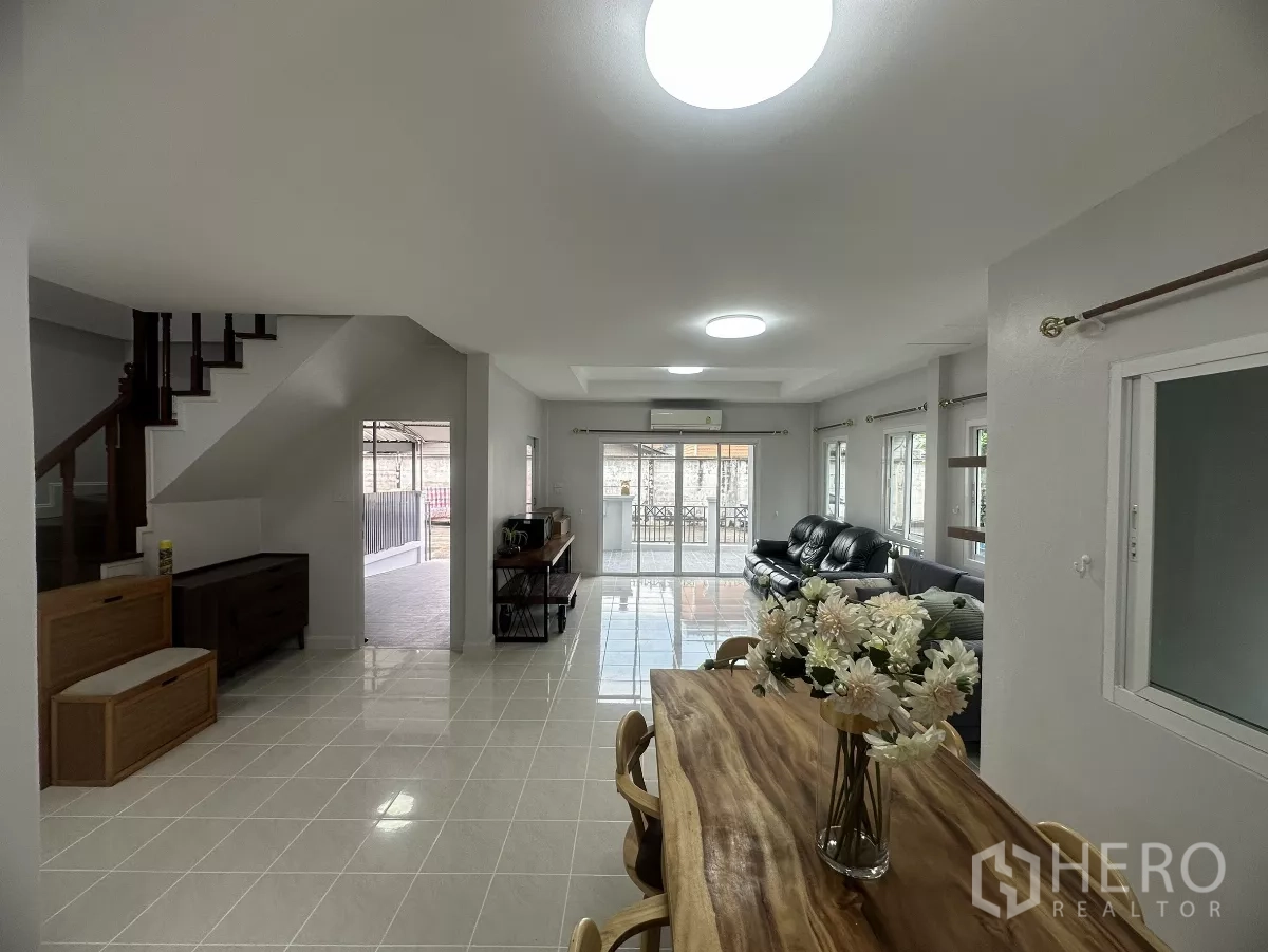 Townhouse for sale in Lam Luk Ka, Pathum Thani - Bright open-plan living and dining room with stairs and sliding glass doors.