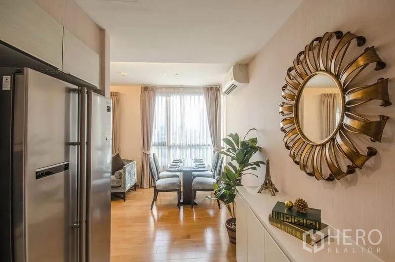 Condominium for rent or sale in Watthana, Bangkok - Hallway to dining area with sunburst mirror, indoor plant and natural light.