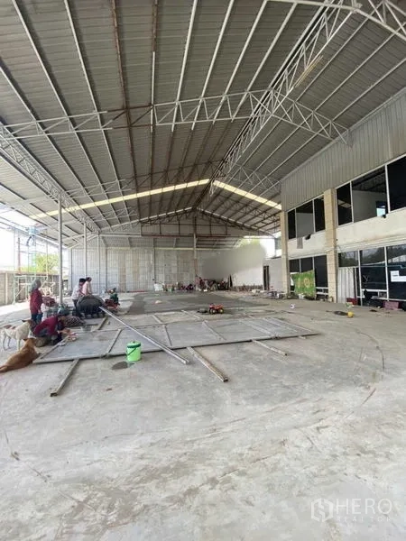 Warehouse for rent in Khlong Luang, Pathum Thani - Open production area under metal truss roof with an adjoining two-storey office block.