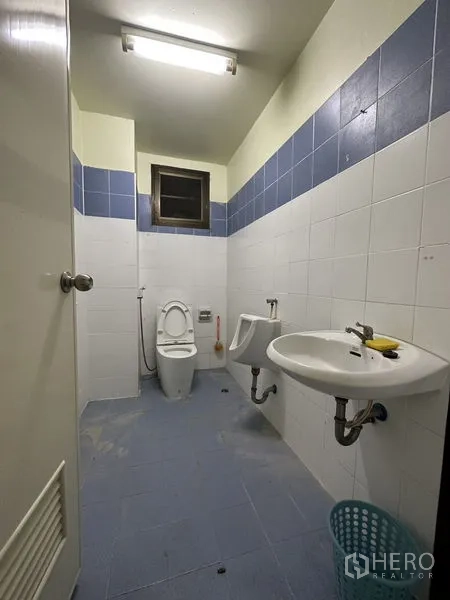 Factory for rent in Bang Bua Thong, Nonthaburi - Restroom with toilet, urinal, sink, and blue-white tiles.