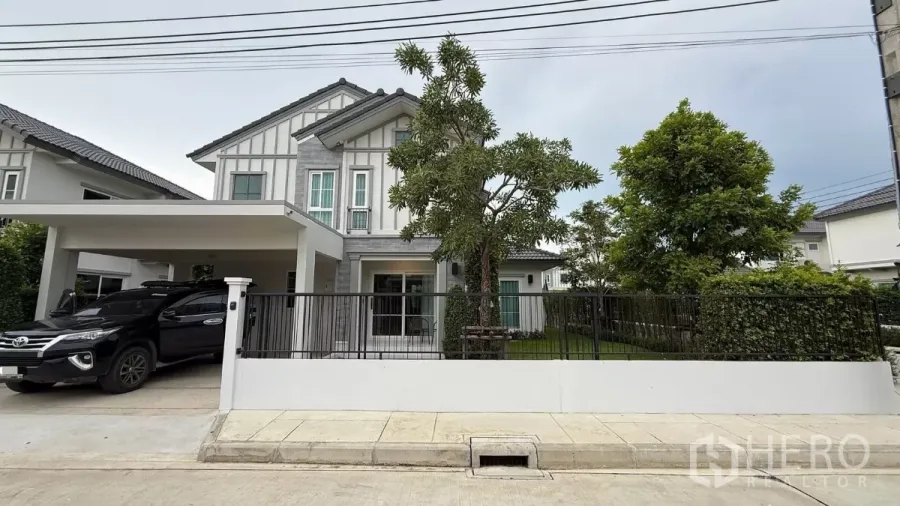 Detached House for rent in Bang Phli, Samut Prakan - Modern two-storey detached house with covered carport and front lawn behind a metal fence.