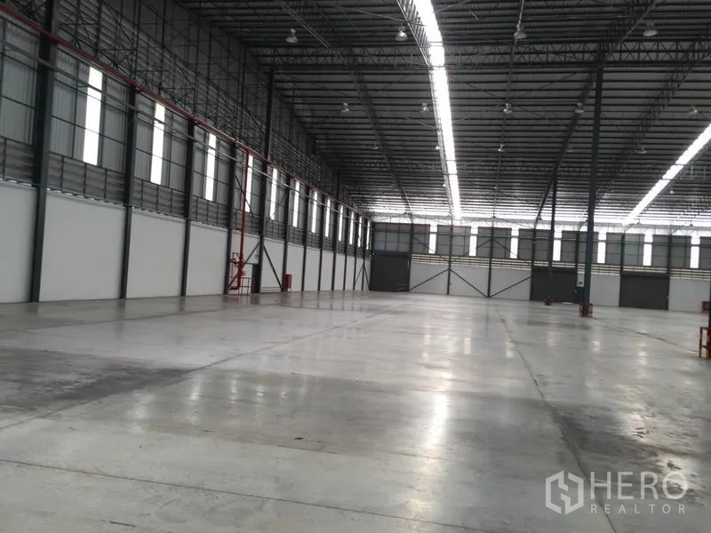 Warehouse for rent in Si Racha, Chon Buri - Warehouse aisle with clerestory windows, smooth concrete floor and visible fire safety equipment.