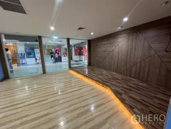 Retail Space for rent in Bang Rak, Bangkok - Wood-look flooring and a feature wall with warm LED strip lighting beside a glass shopfront.