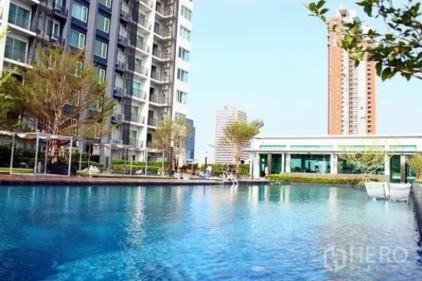 Condominium for rent in Khlong Toei, Bangkok - Condominium outdoor swimming pool with landscaped deck beside mid-rise residential buildings.