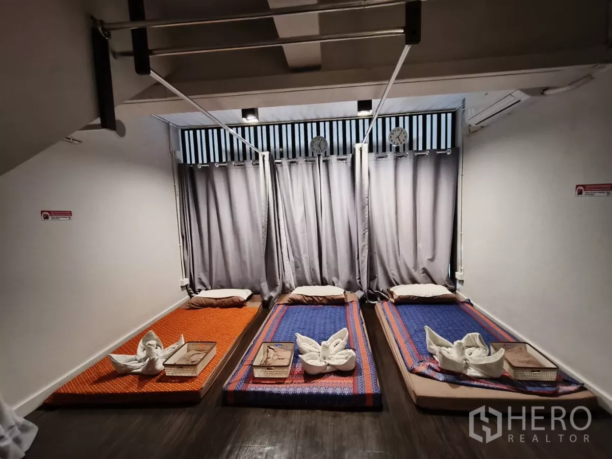 Shophouse for rent in Watthana, Bangkok - Curtained room with three Thai massage floor mats and soft lighting.