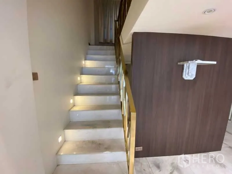 店屋 出租或出售在Watthana, Bangkok - 石材楼梯配黄铜扶手，通往楼上空间。