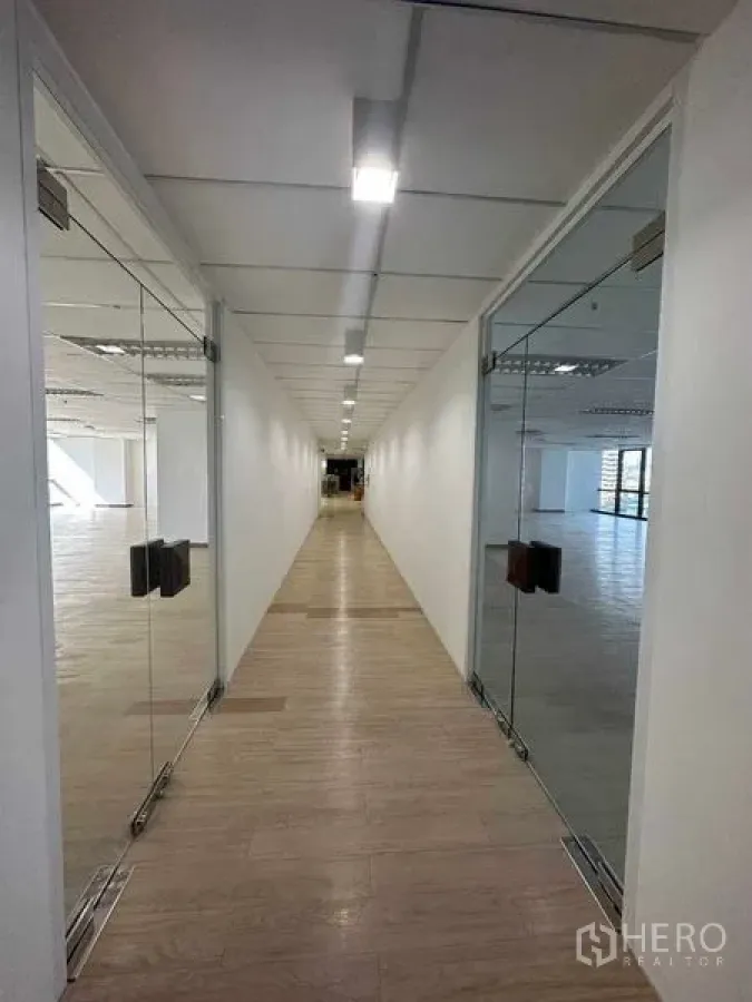 Office Space for rent in Watthana, Bangkok - Well-lit hallway with glass entry doors to office spaces, laminate flooring, and ceiling lights.