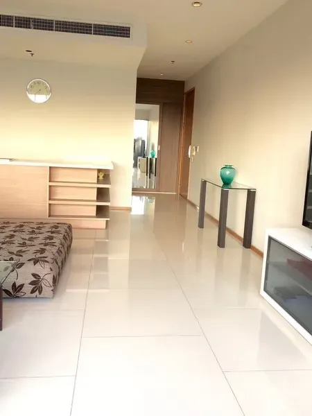 Condominium for rent in Khlong Toei, Bangkok - Hallway and lounge with glossy tiled floors, console table and built-in shelves leading to the bedrooms.