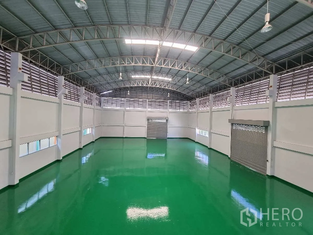Factory for rent in Samut Prakan - Large production hall with high arched roof and polished green epoxy floor.