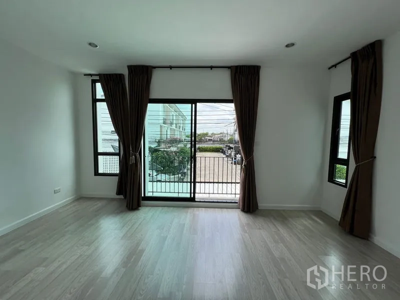 Townhouse for sale in Bang Kapi, Bangkok - Upper-floor room with sliding doors to a balcony overlooking the street.