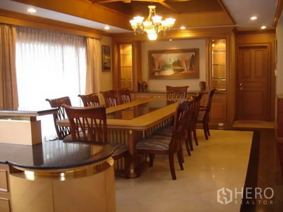 Apartment for rent in Khlong Toei, Bangkok - Formal dining room with long table, chandelier lighting, and glass display cabinets.