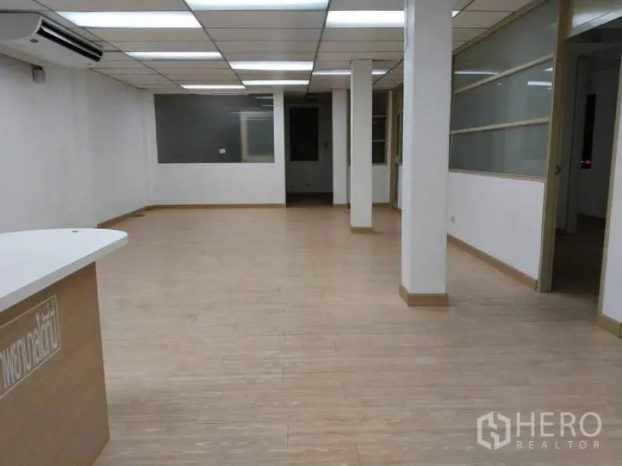 Office Space for rent in Bang Na, Bangkok - Open-plan office interior with wood-look flooring, drop ceiling lights, and glass partitions.