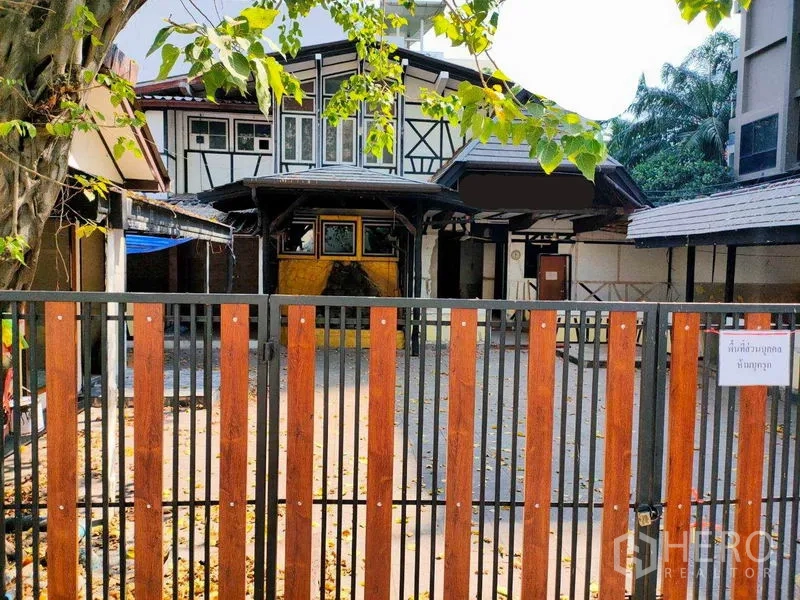 Retail Space for rent in Khlong Toei, Bangkok - Gated retail property with Tudor-style facade, wide front courtyard under a shade tree, and a covered entrance in urban Bangkok.