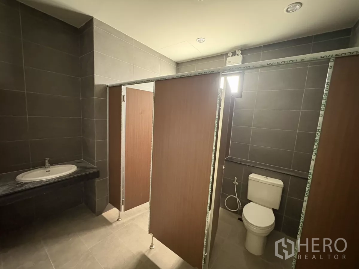 Factory for rent in Bang Pakong, Chachoengsao - Modern restroom with tiled walls, sink and toilet inside the office block.