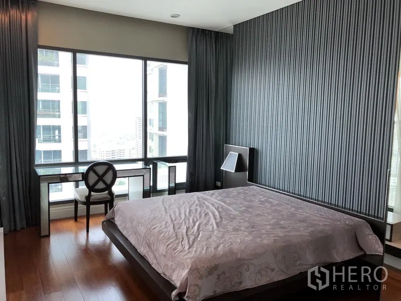 Condominium for rent or sale in Khlong Toei, Bangkok - Bedroom with striped accent wall and work desk by panoramic window.