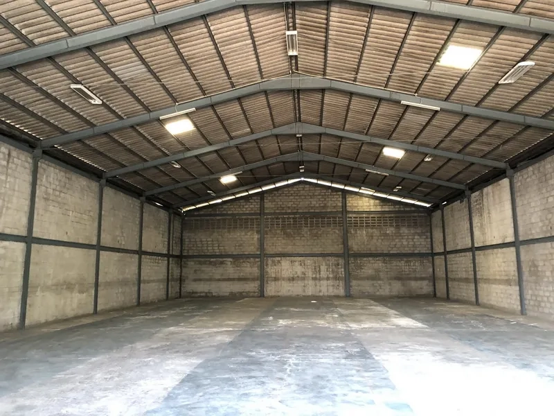 Warehouse for rent in Khlong Luang, Pathum Thani - Spacious clear-span warehouse interior with steel frame, concrete floor and ceiling lights.