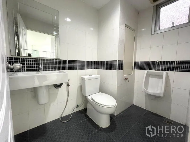 Office Space for rent in Khlong Toei, Bangkok - Clean tiled bathroom with toilet, urinal and wall-mounted sink.