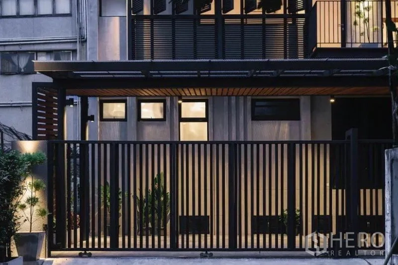 Townhouse for rent in Khlong Toei, Bangkok - Front elevation showing black slatted fence, screened balcony and planted borders.