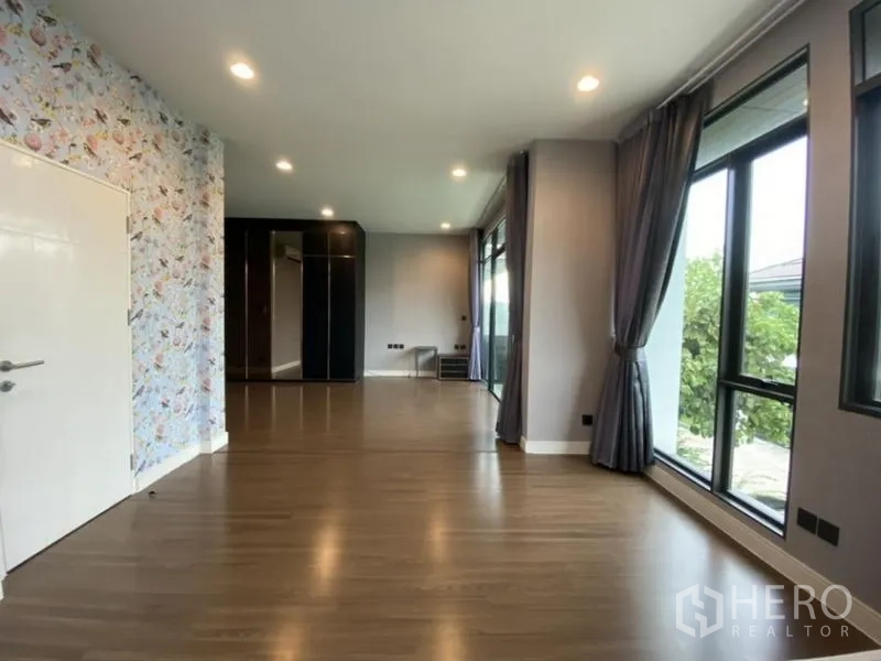 Detached House for rent in Bang Kapi, Bangkok - Expansive upstairs room with wallpaper accent and floor-to-ceiling windows.