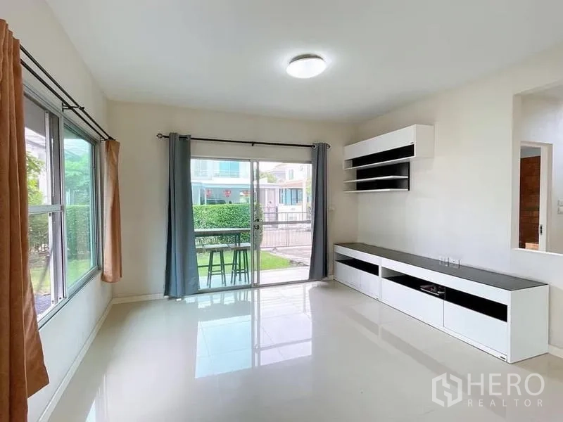 Detached House for rent in Bang Na, Bangkok - Sunny living room with sliding glass doors to the patio and built-in TV cabinet.