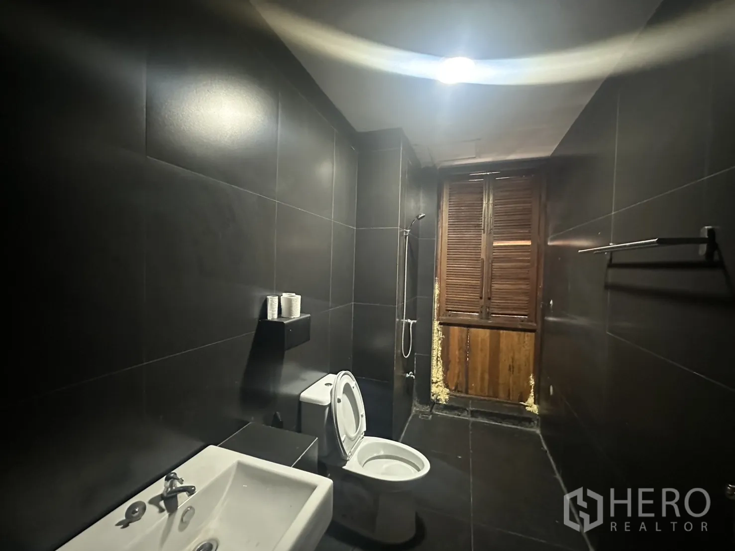 Home Office for rent in Pathum Wan, Bangkok - Bathroom with shower, toilet and window finished in dark tiles.