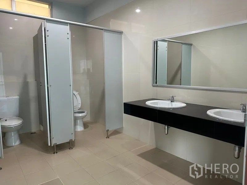 Factory for rent in Bang Phli, Samut Prakan - Modern restroom with cubicles, twin basins and tiled walls.