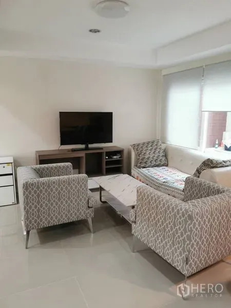 带办公室的家 出租在Chatuchak, Bangkok - 明亮客厅，配花纹沙发、电视柜与瓷砖地面。