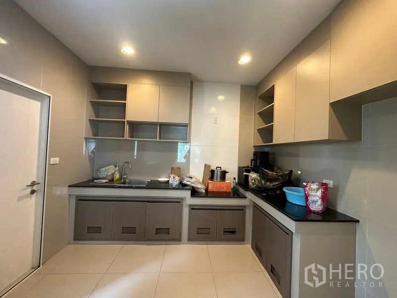 Detached House for rent in Lam Luk Ka, Pathum Thani - Fitted kitchen with ample cabinets, black countertops and tile floor.