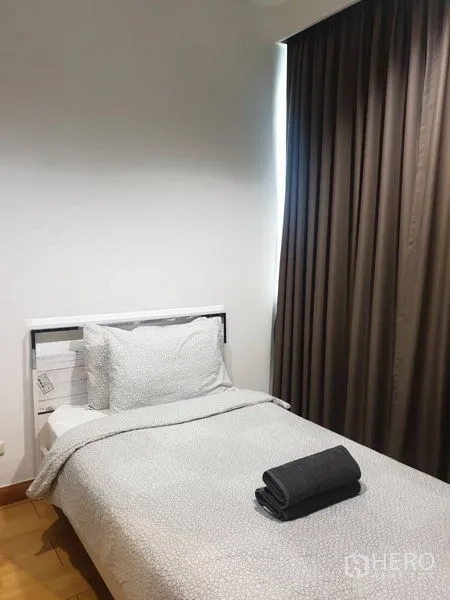 Condominium for rent in Khlong Toei, Bangkok - Cozy bedroom with single bed, soft bedding, and blackout curtains.