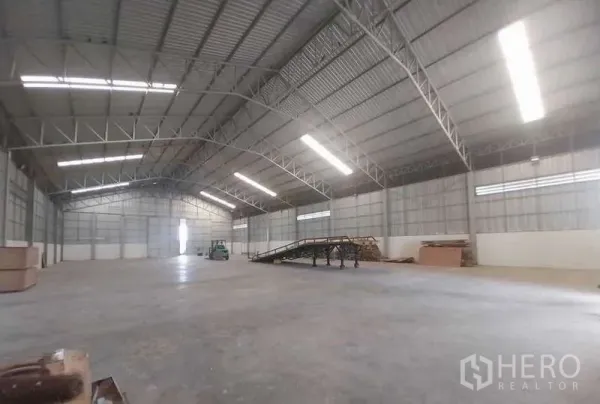 Warehouse for sale in Sai Noi, Nonthaburi - Open-plan storage hall with loading ramp, high-bay lighting and concrete floor.