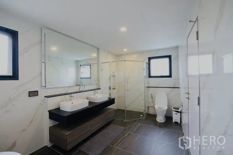 Detached House for rent in Bang Phli, Samut Prakan - Large bathroom with double vanity, glass shower enclosure, and toilet.