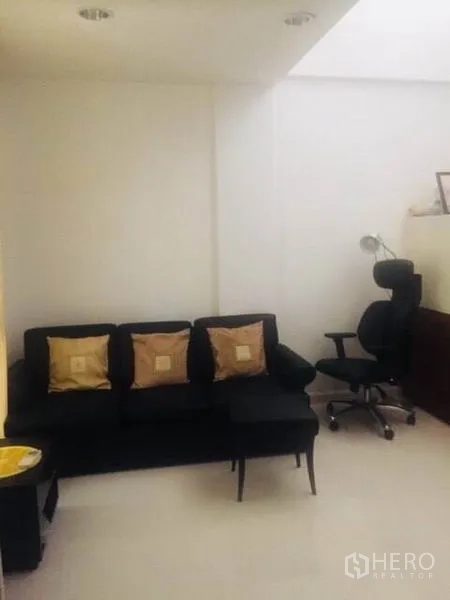 联排别墅 出租在Bang Kapi, Bangkok - 小巧客厅，黑色沙发、抱枕与办公椅。