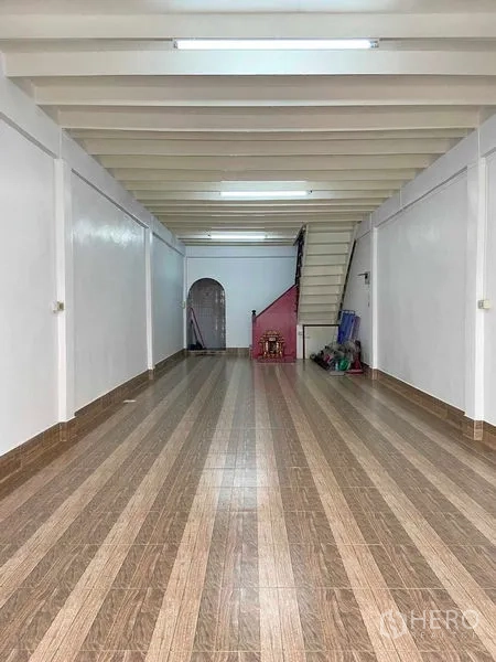 Shophouse for sale in Phra Khanong, Bangkok - Open-plan ground floor of the shophouse with striped tile flooring, exposed beams and a rear staircase.