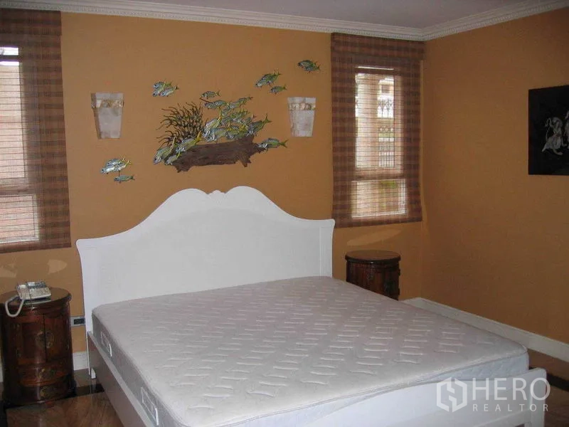 Detached House for rent in Watthana, Bangkok - Bedroom with warm-toned walls, white bed and windows with blinds.