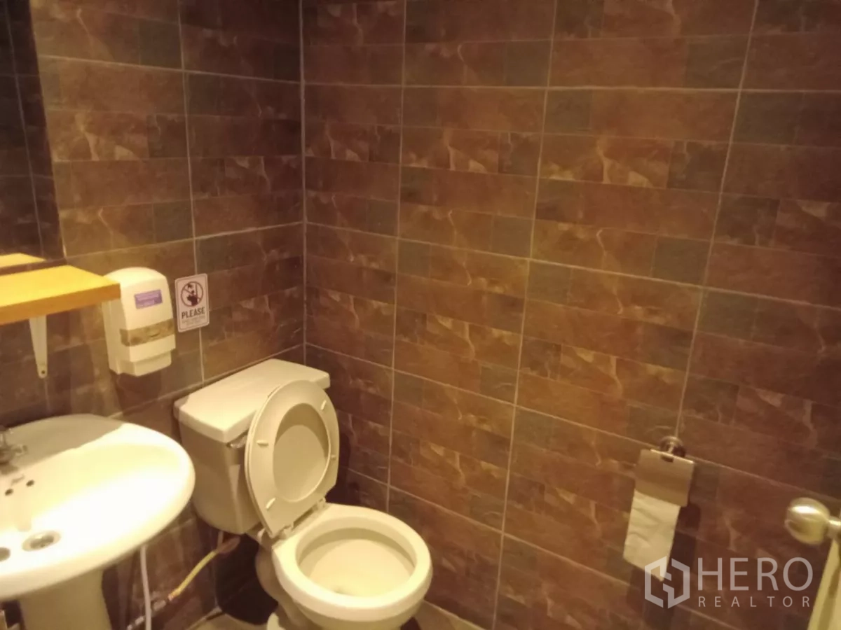 Detached House for rent in Phaya Thai, Bangkok - Bathroom with brown tiled walls, sink and toilet.