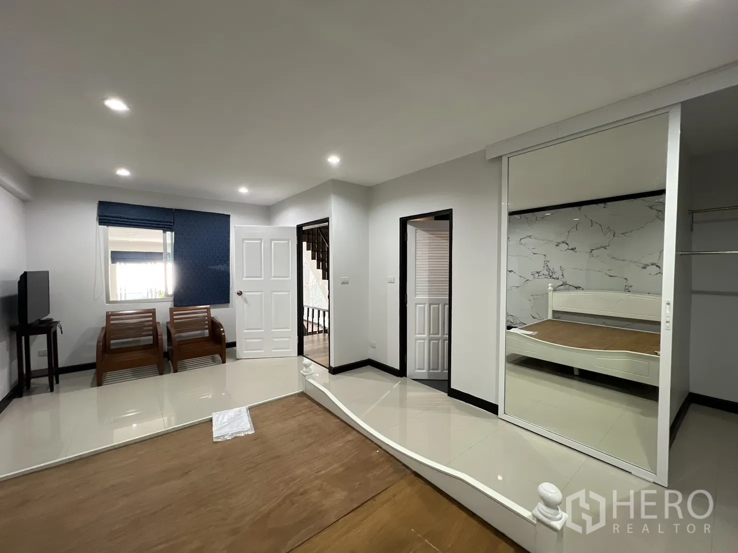 Townhouse for rent in Watthana, Bangkok - Large suite with seating area, TV stand and mirrored wardrobe beside the bed platform.