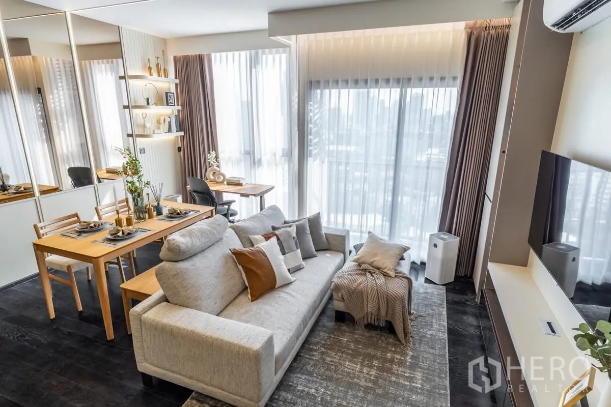 公寓 for rent or sale in Watthana, Bangkok - 明亮的开放式客厅，配沙发、餐桌、书桌、落地窗与墙挂电视