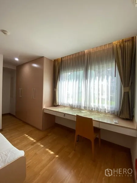 Condominium for rent or sale in Khlong Toei, Bangkok - Bedroom with large window, long study desk and wood flooring for natural light.