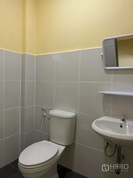Warehouse for rent or sale in Bang Phli, Samut Prakan - Clean tiled restroom with toilet, sink, mirror and wall shelf inside the warehouse.