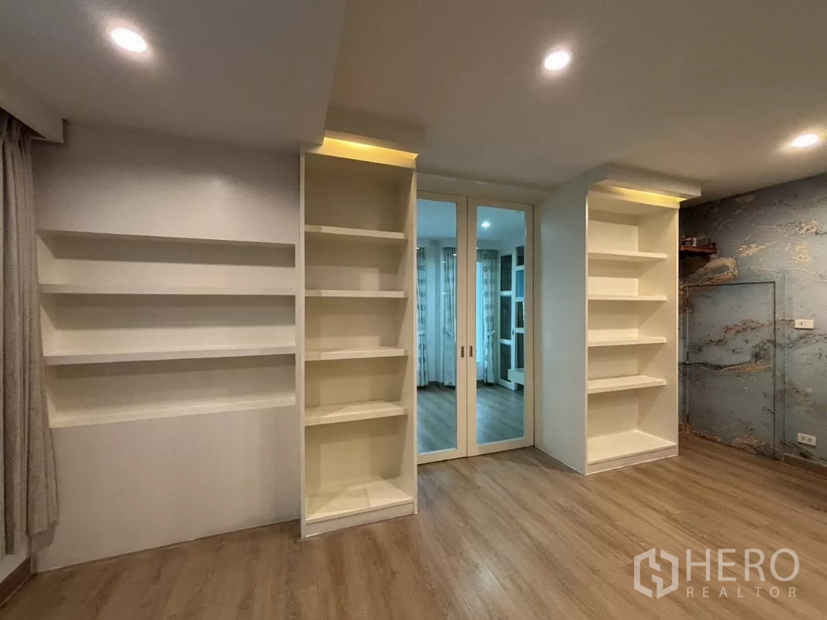 Detached House for rent in Bang Kapi, Bangkok - Built-in wall shelves and mirrored sliding doors in a bright room.