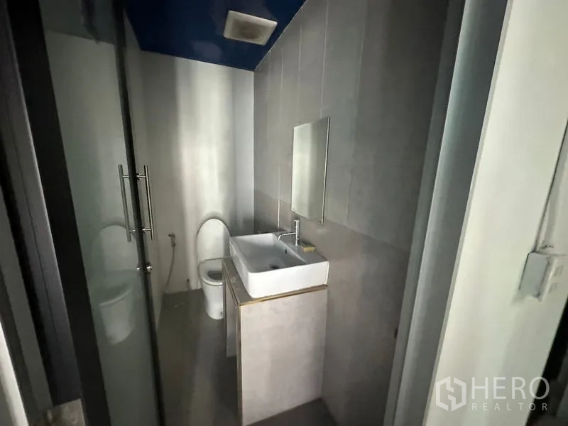 Office Space for rent in Watthana, Bangkok - Compact washroom with glass door, vanity sink and toilet.