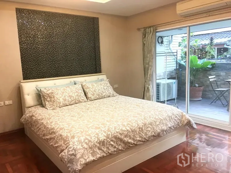 Townhouse for rent in Bang Rak, Bangkok - Master bedroom with king bed, sliding glass door to terrace, air conditioner and parquet floor.