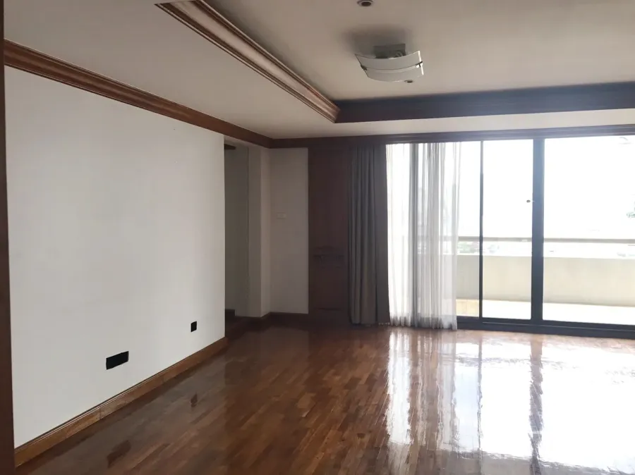 Condominium for rent in Pathum Wan, Bangkok - Bright living room with polished wooden floors and large sliding glass doors opening to a balcony.